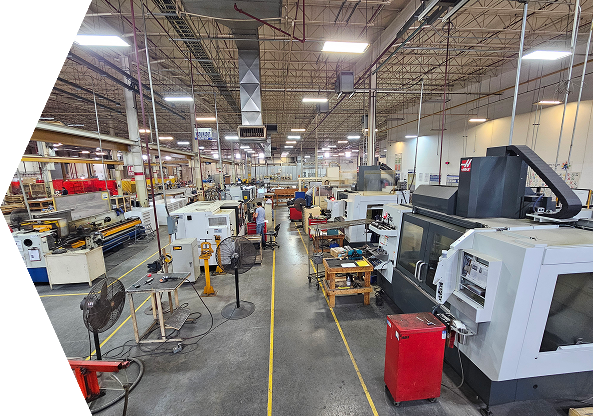A wide interior shot of a well-lit, industrial machine shop featuring rows of CNC machinery and equipment stretching down a central aisle marked with yellow safety lines.